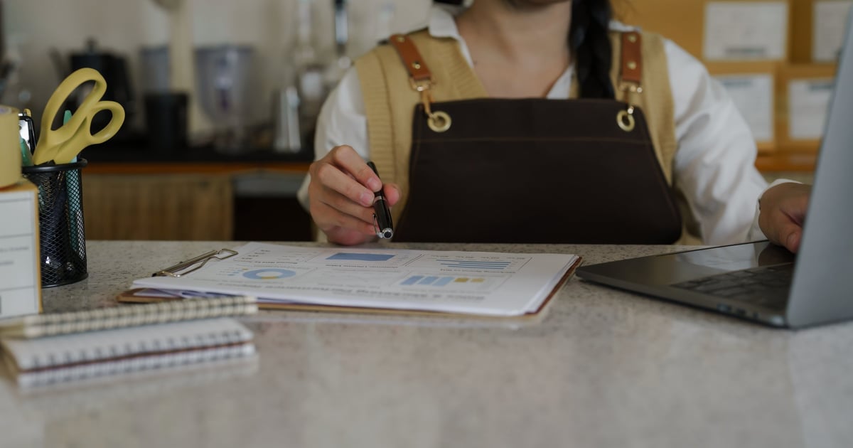 Propietario de un restaurante analizando reportes financieros, datos de costos y margen en una laptop durante una sesión de análisis de rentabilidad